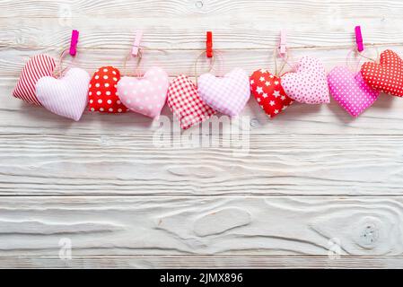 Valentine Stoffherzen an Seil auf weißem Holzhintergrund gehängt Stockfoto