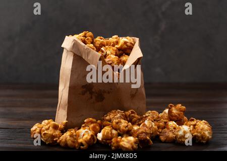 Karamellisiertes Popcorn in einer Papiertüte auf einem hölzernen Küchentisch Stockfoto