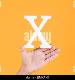 Weibliche Hand mit weißem Alphabet x Stockfoto