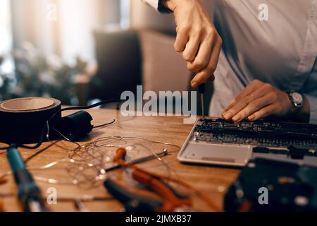 Der letzte Schliff. Eine unkenntliche Computertechnikerin repariert einen Laptop in ihrer Werkstatt. Stockfoto