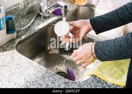 Nahaufnahme Frau s Hand Waschbecher Spülbecken Küche Stockfoto