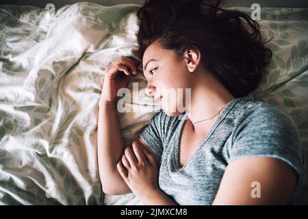 Ich wünschte mir, das Leben wäre jetzt ein wenig freundlicher zu mir. Eine attraktive junge Frau, die deprimiert auf ihrem Bett zu Hause liegt, wurde aus einem hohen Winkel aufgenommen. Stockfoto