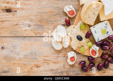 Käseplatten mit Weintrauben, Brot, Holztisch Stockfoto