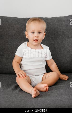 Baby Junge sitzend Sofa warten essen Stockfoto