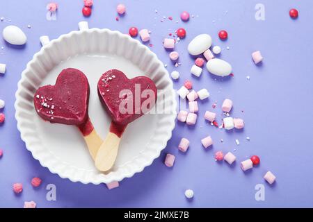 Violettes Heidelbeer-Eis auf lilafarbenem Hintergrund. Stimmungsvolles, süßes Menükonzept. Draufsicht, flach liegend, Kopierbereich Stockfoto