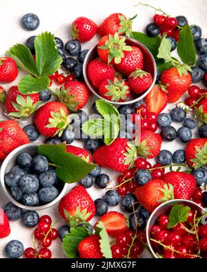 Verschiedene frische Beeren auf neutralem Hintergrund. Organische wertvolle Nahrungsquelle. Draufsicht Stockfoto