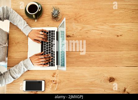 Mein Blog wird aktualisiert. Eine nicht erkennbare Geschäftsfrau, die allein in einem Gebäude sitzt und mit ihrem Laptop bloggt. Stockfoto