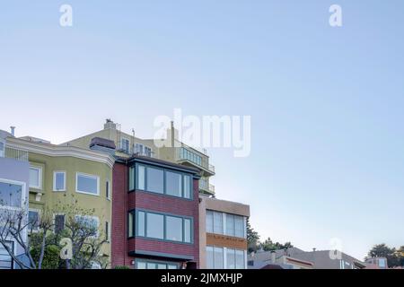Blick auf farbenfrohe komplexe Wohngebäude vor dem Sonnenuntergangshimmel in San Francisco, CA. Fassade von Gebäuden mit verschiedenen Fensterstrukturen und w Stockfoto