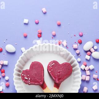 Violettes Heidelbeer-Eis auf lilafarbenem Hintergrund. Stimmungsvolles, süßes Menükonzept. Draufsicht, flach liegend, Kopierbereich Stockfoto