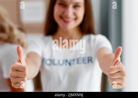 Frontansicht Unschärfe-gebende weibliche Freiwillige gibt Daumen nach oben Stockfoto
