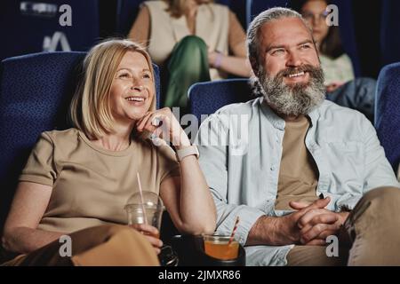 Horizontales mittleres Porträt eines erwachsenen kaukasischen Mannes und einer Frau, die am Wochenende einen Film im Kino sehen Stockfoto