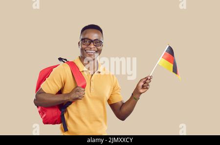 Glücklicher afroamerikanischer Student mit deutschlandflagge isoliert auf hellbeigem Hintergrund. Stockfoto