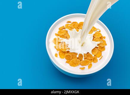 Maisflocken mit Milch auf blauem Hintergrund, Draufsicht Stockfoto