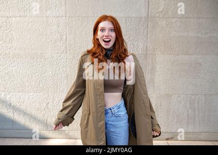 Glücklich aufgeregt teen rothaarige Mädchen stehen auf Stadtmauer Hintergrund. Stockfoto