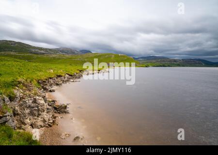 Ein Landschaftsblick auf Loch Assynt mit den Ruinen des Calda House im Hintergrund Stockfoto