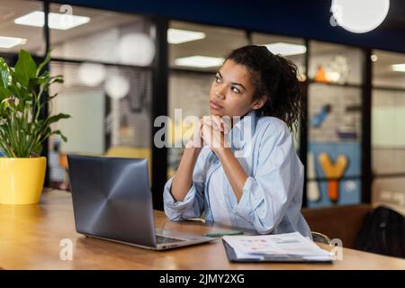Nachdenkliche Frau im Büro mit Laptop Stockfoto