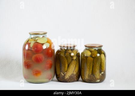 Hausgemachte Tomaten und Gurken aus der Dose in Gläsern auf weißem Hintergrund in Nahaufnahme Stockfoto