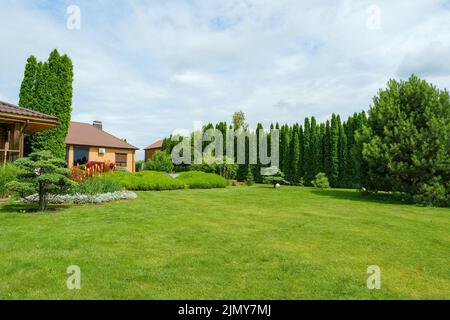 Landhaus auf Rasen in der Nähe von üppigen grünen Wäldern Stockfoto