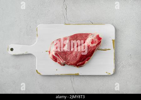 Draufsicht auf rohes Lammbein, das als Steak geschnitten wurde. Schaftscheibe auf weißem Schneidebrett Stockfoto