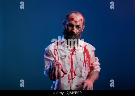 Portrait von halloween Zombie mit Narben und blutigen Wunden posiert vor der Kamera, gefährliche Untote Leiche mit gruseligen Kratzern und gruseliges Gesicht im Studio. Weltuntergang grausamer Monsterteufel. Stockfoto