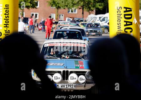 Kiel, Deutschland. 08. August 2022. Die Zuschauer beobachten den Beginn der Wiederbelebung der Olympischen Rallye 1972. 197 Teams mit Fahrzeugen von 44 verschiedenen Automarken, die zwischen 1950 und 1990 gebaut wurden, werden in sechs Etappen nach München kommen. Quelle: Frank Molter/dpa/Alamy Live News Stockfoto