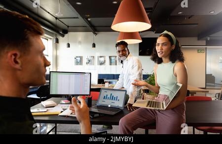 Mehrrassische Kollegen und Kolleginnen diskutieren über den Plan am Laptop in der Besprechung im Büro Stockfoto