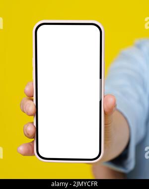 Frau Hand hält Smartphone mit weißem Bildschirm in rosa Fall isoliert auf gelbem Hintergrund. Modernes Telefon mit Touchscreen in Frauenhand. Nahaufnahme. Werbung für mobile Anwendungen nachmachen. Stockfoto