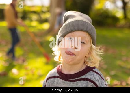Bild eines glücklichen kaukasischen Jungen, der im Garten lustige Gesichter macht Stockfoto
