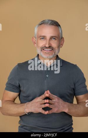 Grauhaariger lächelnder Mann, der selbstbewusst aussieht Stockfoto