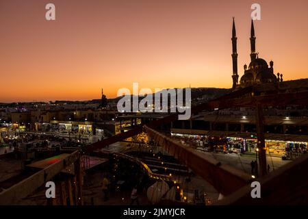 Sharm El Sheikh, Ägypten - 4. November 2021: Panoramablick von oben auf die Al Sahab Moschee und die Altstadt bei Sonnenuntergang. Silhouetten von Menschen im Einkaufsviertel mit Souvenirs im Schein von Nachtlichtern. Stockfoto