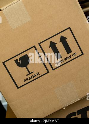 Angewinkelter Karton mit den Worten Fragile und This Way Up, zusammen mit grafischen Symbolen. Stockfoto