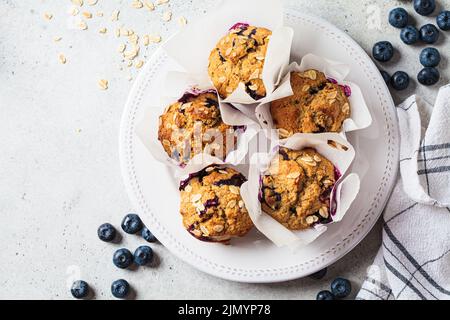 Vegane Haferflocken, Banane, Blaubeer-Muffins auf grauem Hintergrund, Draufsicht. Dessert auf pflanzlicher Basis. Stockfoto
