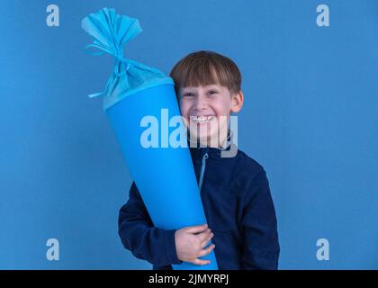 Kind hält am ersten Schultag traditionellen deutschen Süßigkeitenkegel. Junge mit einer süßen Tasche. Schulbeginn in Deutschland Stockfoto