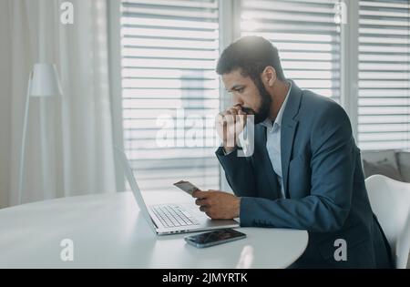 Deprimierter Geschäftsmann Mann, der Euro-Geld zählt und am Schreibtisch am Computer arbeitet, Inflationskonzept. Stockfoto
