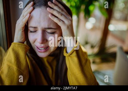 Frau, die an Depressionen leidet und zu Hause weint und den Kopf in den Händen hält. Stockfoto