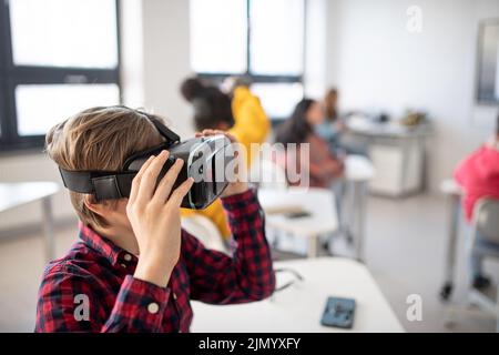 Neugieriger Schüler mit Virtual-Reality-Brille in der Schule im Informatikunterricht Stockfoto