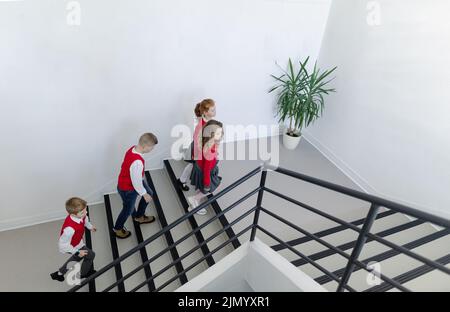 Ansicht von Schulkindern in Uniformen, die im Treppenhaus der Schule laufen. Stockfoto