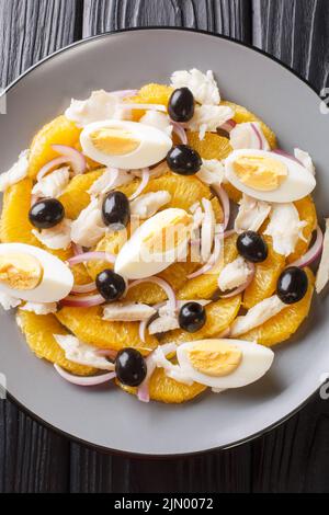 Spanische Küche Remojon-Kabeljau, Ei, Oliven-, Zwiebel- und Orangensalat in Nahaufnahme auf einem Teller auf dem Tisch. Vertikale Draufsicht von oben Stockfoto