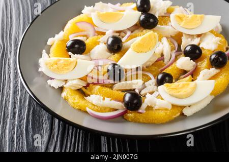 Remojon Andaluz enthält frische Orangen, Zwiebel, gekochte Eier, schwarze Oliven und köstlichen Salz-Kabeljau aus nächster Nähe auf einem Teller auf dem Tisch. Horizontal Stockfoto