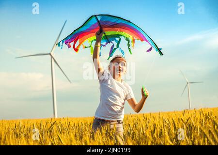 Glückliches kleines Mädchen, das im Sommer auf einem Weizenfeld mit einem Drachen läuft. Stockfoto