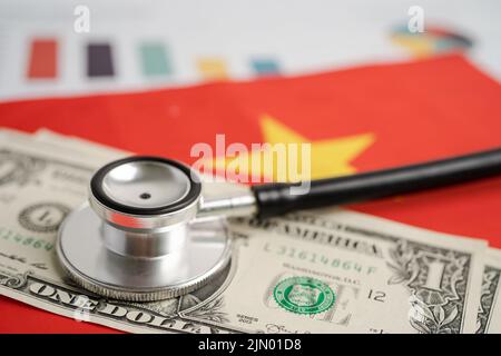 Schwarzes Stethoskop auf Vietnam Flagge Hintergrund mit Grafik, Business und Finanzen Konzept. Flagge Hintergrund mit US-Dollar-Banknoten, Business und Finanzen Stockfoto