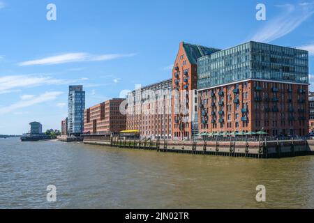 Hamburg, 3. August 2022: Moderne Gebäude aus rotem Backstein und Glas aus ehemaligen Lagerhäusern an der Elbe, blauer Himmel mit Kopierfläche, ausgewählt Stockfoto