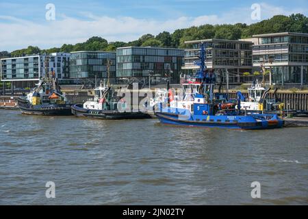 Hamburg, 3. August 2022: Schleppschiffe in Reihe im Hamburger Hafen vor modernen Gebäuden schleppen sie große Schiffe und Frachter nach Hamburg Stockfoto