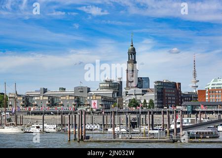 Hamburg, 3. August 2022: Stadtbild mit Michaelskirche namens Michel und Kai des internationalen Hafens an der Elbe, blauer Himmel wi Stockfoto