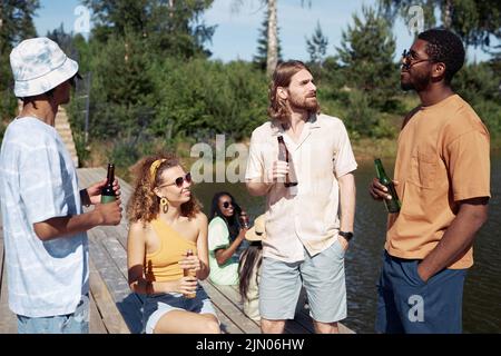 Eine vielfältige Gruppe junger Menschen, die im Sommer erfrischende Getränke im Freien genießen Stockfoto
