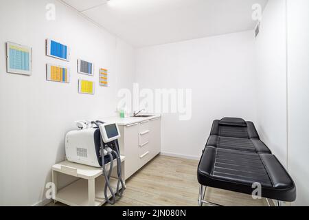 Leerer Salon für ästhetische Medizin. Moderner leerer Dermatologe Kosmetikmassagetisch für Eingriffe in der Schönheitsklinik. Stockfoto