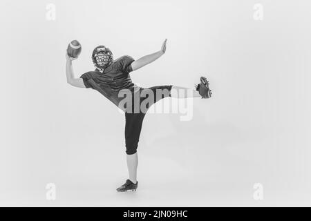 Studio-Aufnahme des american Football Spieler Training mit Ball isoliert auf weißem Hintergrund. Konzept von Sport, Leistungen, Retro-Stil. Monochrom Stockfoto