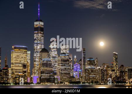 Das Stadtbild der Gebäude in New York City bei Nacht mit Vollmond am Himmel Stockfoto