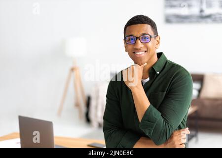 Porträt eines erfolgreichen jungen afroamerikanischen Geschäftsmannes mit Brillen, die im modernen Büro stehen Stockfoto