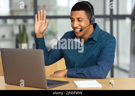 Erfolgreicher Mann im Headset-Büro oder Callcenter-Mitarbeiter, der mit einem Lächeln für Videogespräche mit dem Kunden spricht Stockfoto